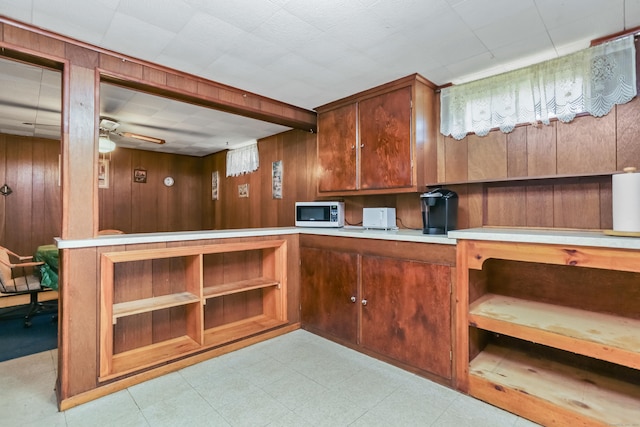 97 Travis Dr, Bridgeport, CT 06606 - kitchen with stainless steel microwave, a ceiling fan, wooden walls, light countertops, and light floors