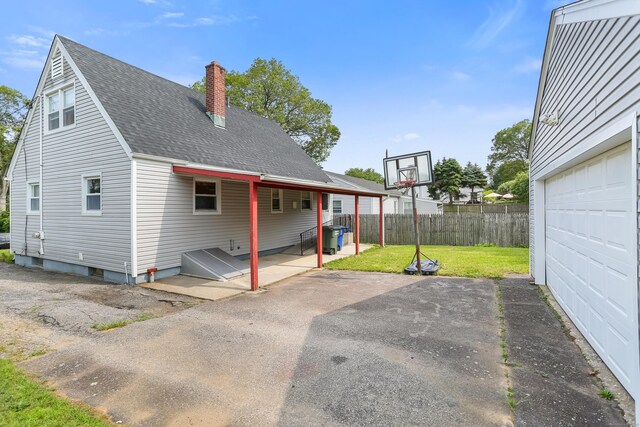 97 Travis Dr, Bridgeport, CT 06606 - back of house featuring a garage, a chimney, roof with shingles, asphalt driveway, and a patio