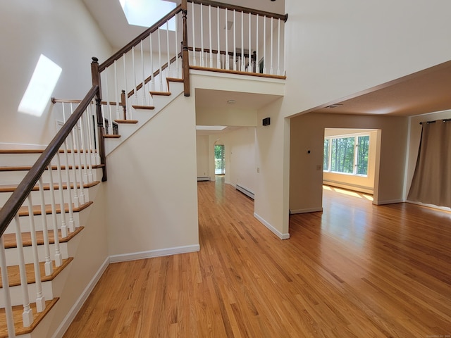 12 Enrico Rd, Bolton, CT 06043 - staircase with a baseboard radiator, wood finished floors, a skylight, and a high ceiling