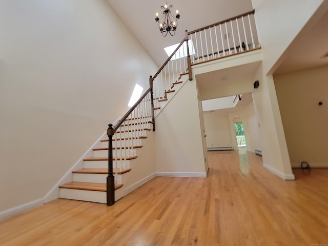 12 Enrico Rd, Bolton, CT 06043 - stairway featuring wood finished floors, a towering ceiling, a chandelier, and a baseboard radiator