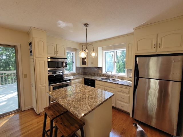12 Enrico Rd, Bolton, CT 06043 - kitchen with appliances with stainless steel finishes, light wood-style floors, tasteful backsplash, a breakfast bar, and a textured ceiling