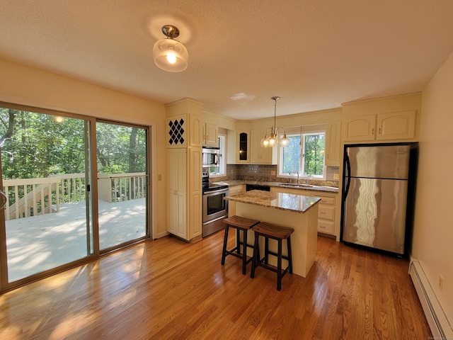 12 Enrico Rd, Bolton, CT 06043 - kitchen featuring appliances with stainless steel finishes, a baseboard heating unit, light wood finished floors, backsplash, and a textured ceiling