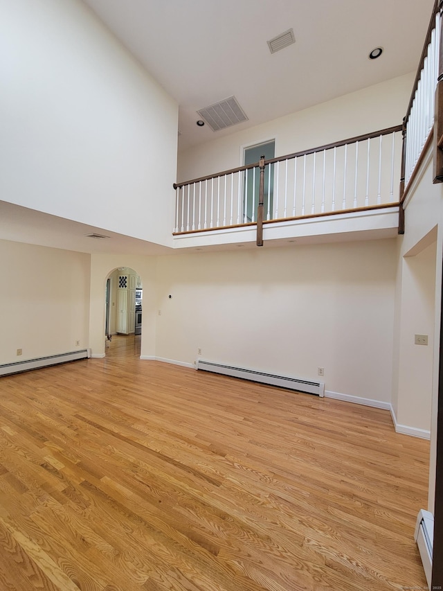 12 Enrico Rd, Bolton, CT 06043 - unfurnished living room with baseboard heating, a high ceiling, arched walkways, and light wood-style floors