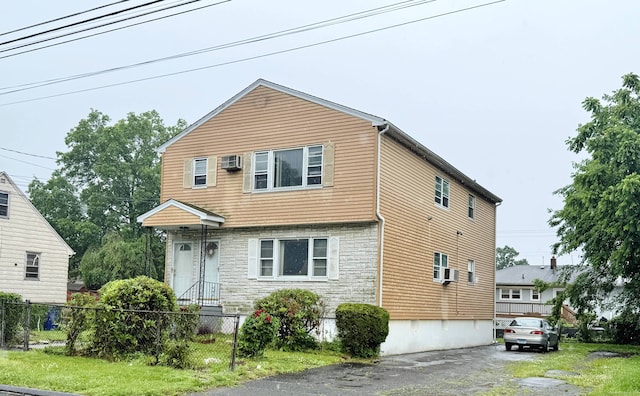 view of front facade featuring stone siding and a wall mounted AC