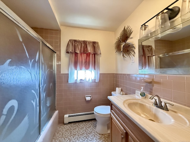 bathroom with a baseboard radiator, tile walls, vanity, bath / shower combo with glass door, and wainscoting
