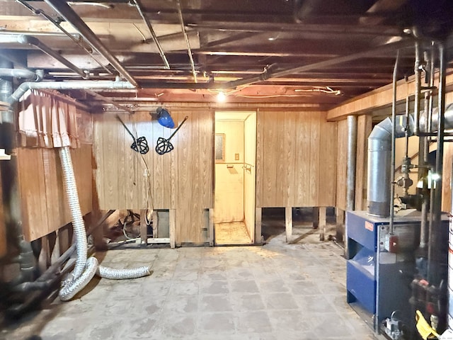 unfinished basement with wooden walls and a heating unit