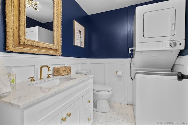 1207 Stillson Rd, Fairfield, CT 06824 - bathroom featuring stacked washer / drying machine, marble look tiles, vanity, wainscoting, and a decorative wall