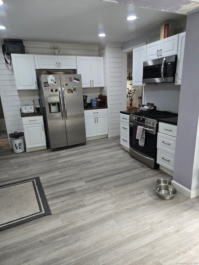 138 Harwinton Ave, Torrington, CT 06790 - kitchen featuring appliances with stainless steel finishes, dark countertops, white cabinetry, light wood-style floors, and recessed lighting