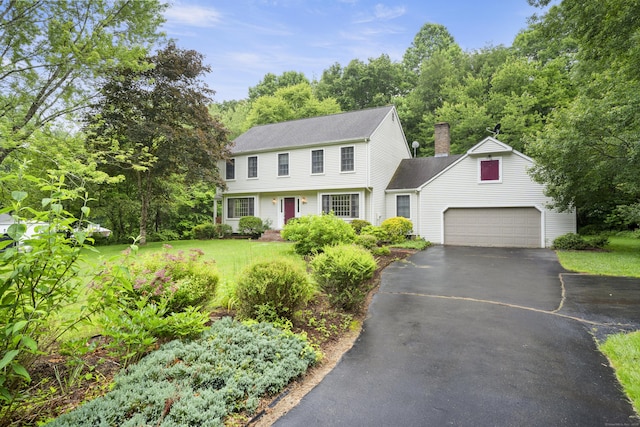 270 N Bride Brook Rd, East Lyme, CT 06333 - colonial-style house featuring asphalt driveway, a chimney, a garage, roof with shingles, and a front lawn