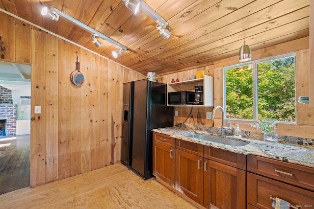 57 River Rd, Clinton, CT 06413 - kitchen featuring black appliances, brown cabinets, wooden walls, light stone counters, and light wood-type flooring