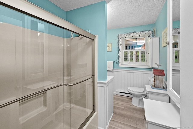 47 Little Bungee Hill Rd, Woodstock, CT 06282 - bathroom featuring baseboard heating, wood finished floors, a shower with shower door, a textured ceiling, and a wainscoted wall