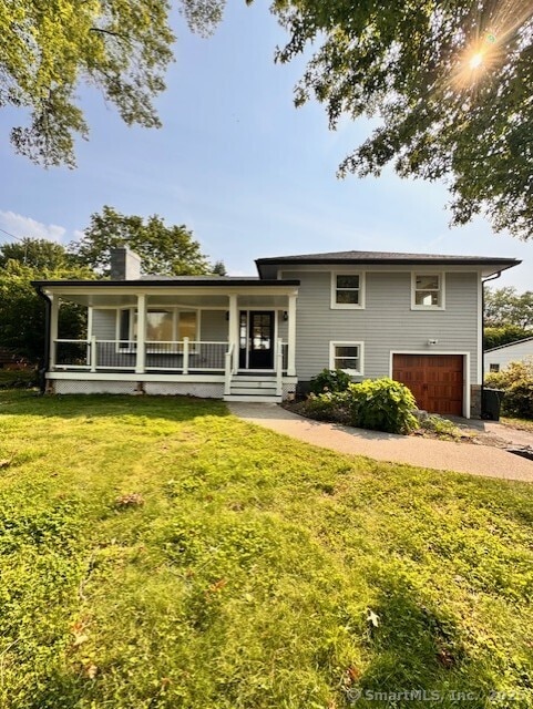 3481 Park Ave, Fairfield, CT 06825 - split level home with an attached garage, a chimney, covered porch, and a front yard