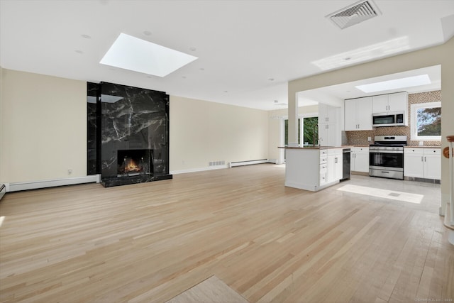 3481 Park Ave, Fairfield, CT 06825 - unfurnished living room with a skylight, light wood-style flooring, a premium fireplace, and a baseboard radiator