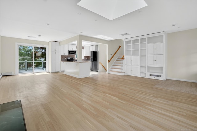 3481 Park Ave, Fairfield, CT 06825 - unfurnished living room featuring light wood-style flooring, stairway, and a skylight