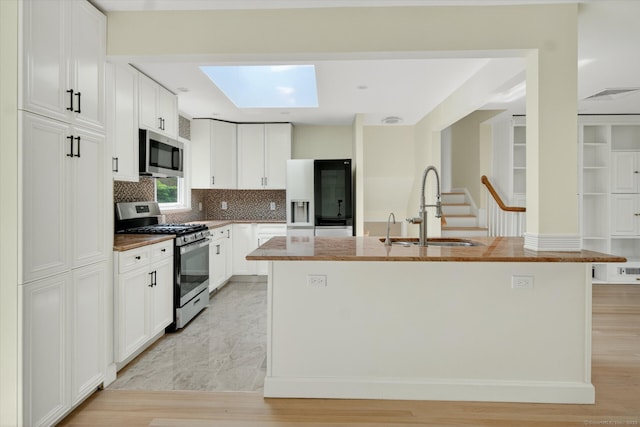 3481 Park Ave, Fairfield, CT 06825 - kitchen with appliances with stainless steel finishes, decorative backsplash, white cabinetry, a skylight, and a center island with sink