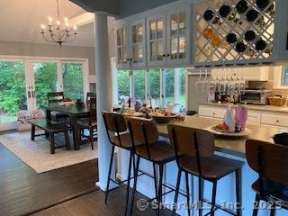 7 White Birch Rd, Wilton, CT 06897 - bar featuring a chandelier, decorative columns, and dark wood finished floors