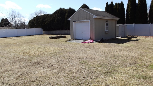 fenced backyard featuring a storage shed and a detached garage