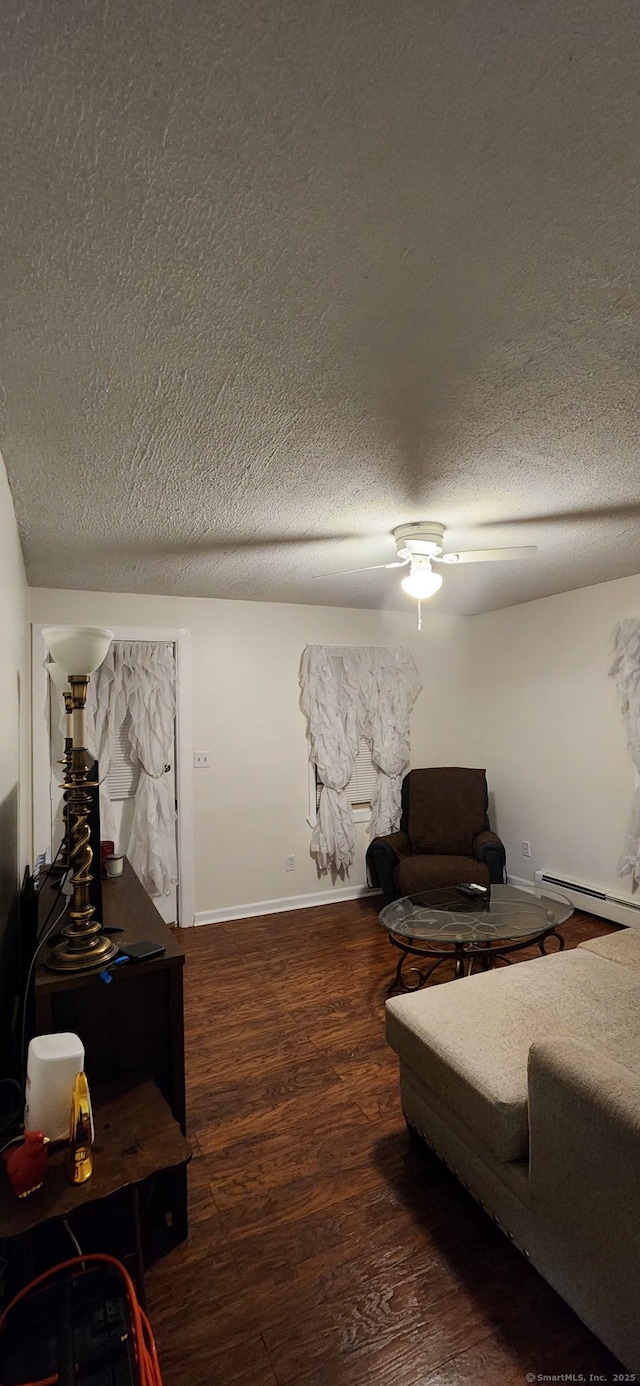 living area with a baseboard heating unit, a textured ceiling, wood finished floors, and ceiling fan