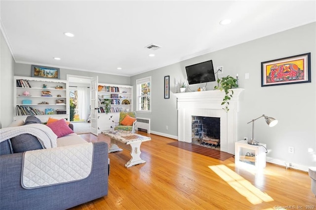 154 Mohawk Dr, West Hartford, CT 06117 - living room with radiator, a fireplace with flush hearth, crown molding, recessed lighting, and wood finished floors
