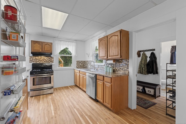 135 W Thames St, Norwich, CT 06360 - kitchen featuring stainless steel appliances, under cabinet range hood, light wood-style flooring, tasteful backsplash, and brown cabinetry