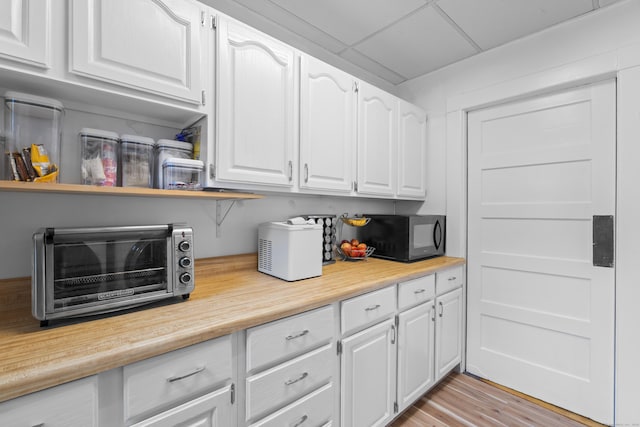 135 W Thames St, Norwich, CT 06360 - kitchen featuring black microwave, light countertops, white cabinetry, and light wood-style floors