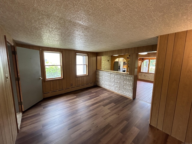 306 Divinity St, Bristol, CT 06010 - unfurnished living room with a baseboard radiator, dark wood-style flooring, a textured ceiling, and wooden walls