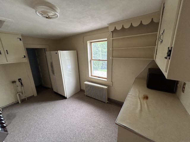 306 Divinity St, Bristol, CT 06010 - kitchen featuring radiator heating unit, freestanding refrigerator, white cabinetry, and light countertops