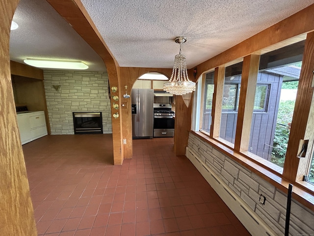 306 Divinity St, Bristol, CT 06010 - unfurnished dining area with washer / dryer, a textured ceiling, a stone fireplace, a chandelier, and baseboard heating