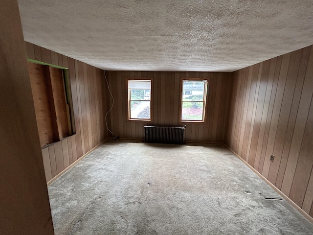 306 Divinity St, Bristol, CT 06010 - empty room featuring radiator, a textured ceiling, carpet, and wooden walls