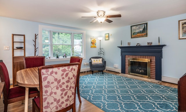 244 Stanwood Dr, New Britain, CT 06053 - dining room with a ceiling fan, a baseboard radiator, a brick fireplace, and wood finished floors