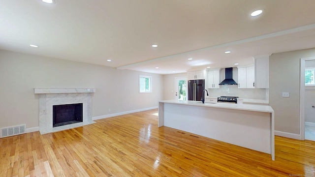 32 Miles Standish Dr, West Hartford, CT 06107 - kitchen with wall chimney exhaust hood, appliances with stainless steel finishes, white cabinetry, light wood-type flooring, and healthy amount of natural light