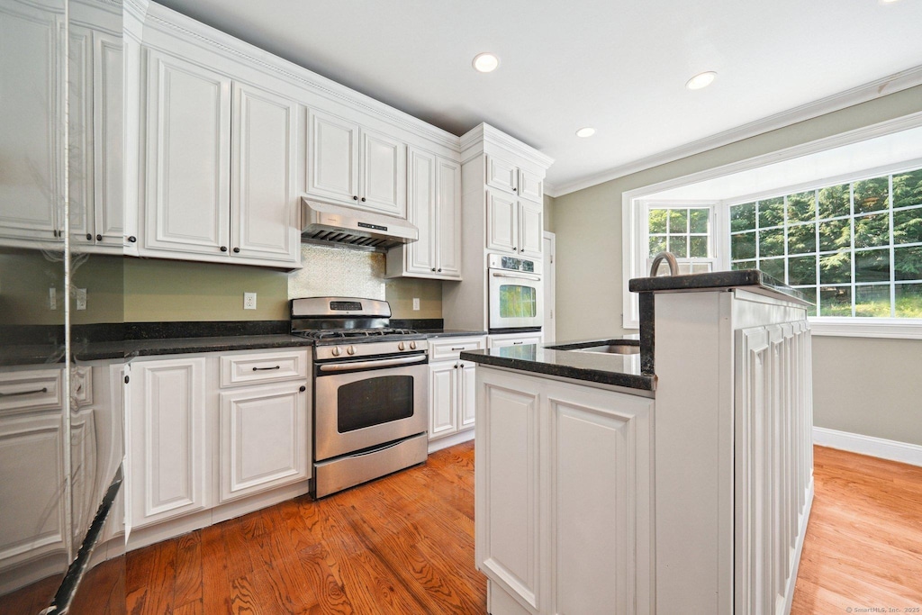 83 Cottage St, Trumbull, CT 06611 - kitchen with gas range, under cabinet range hood, white oven, white cabinets, and light wood-style floors