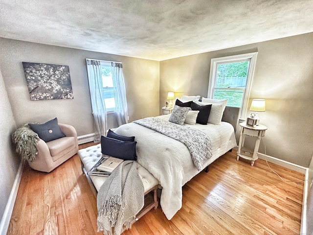 342 Middle Tpke E, Manchester, CT 06040 - bedroom featuring baseboard heating, multiple windows, wood finished floors, and a textured ceiling