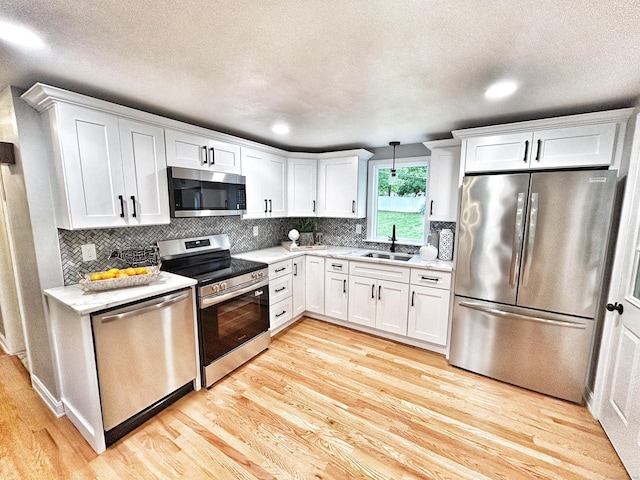 342 Middle Tpke E, Manchester, CT 06040 - kitchen with stainless steel appliances, light wood-style floors, white cabinets, backsplash, and a textured ceiling