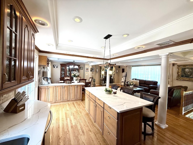 44 Fawn Hill Rd, Shelton, CT 06484 - kitchen featuring light wood finished floors, a kitchen bar, ornate columns, open floor plan, and crown molding