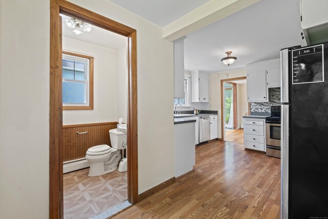 136 Bloomfield Ave, Windsor, CT 06095 - kitchen featuring appliances with stainless steel finishes, a baseboard heating unit, white cabinets, a wainscoted wall, and dark countertops