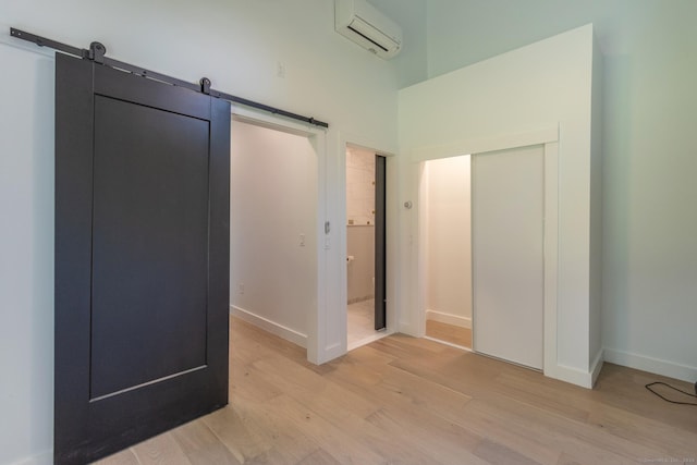 376 Rte 165, Preston, CT 06365 - unfurnished bedroom with a wall mounted AC, light wood-style flooring, a barn door, and a closet