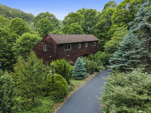 96 Pine Mountain Rd, Ridgefield, CT 06877 - view of property exterior with asphalt driveway, a forest view, a shingled roof, and a garage