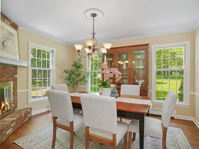 5 September Ln, Weston, CT 06883 - dining area with a chandelier, ornamental molding, wood finished floors, a baseboard radiator, and a fireplace