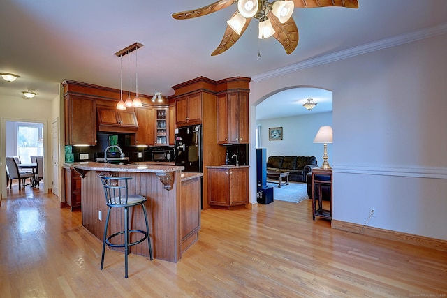 125 Waverly Dr, Newington, CT 06111 - kitchen with a kitchen breakfast bar, arched walkways, ceiling fan, brown cabinetry, and crown molding