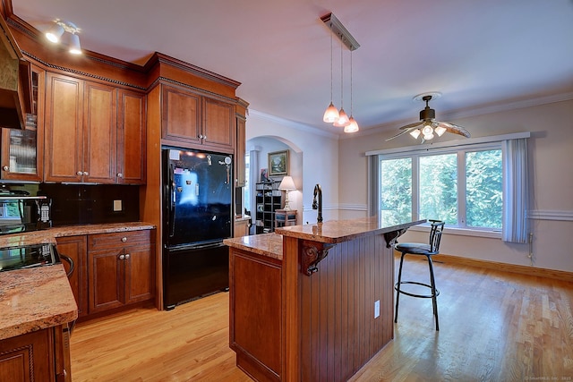 125 Waverly Dr, Newington, CT 06111 - kitchen with freestanding refrigerator, arched walkways, brown cabinetry, ceiling fan, and crown molding
