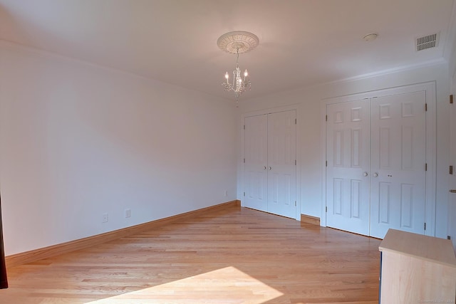 125 Waverly Dr, Newington, CT 06111 - unfurnished bedroom with multiple closets, a chandelier, and light wood finished floors