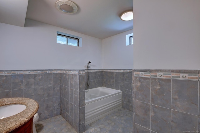 125 Waverly Dr, Newington, CT 06111 - bathroom featuring tile walls, a garden tub, vanity, plenty of natural light, and a wainscoted wall