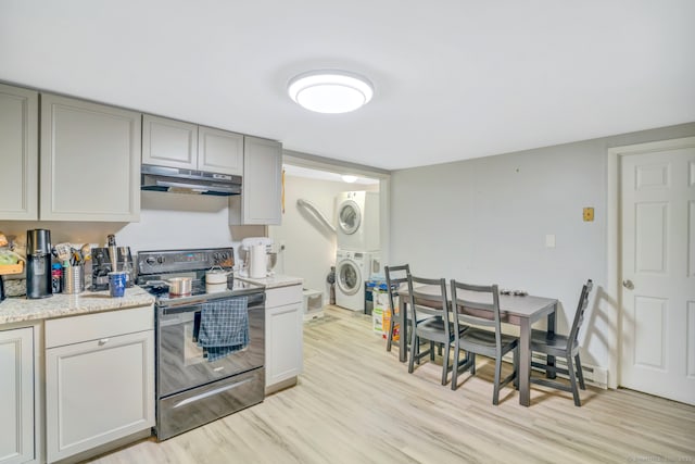 350 S Main St, Naugatuck, CT 06770 - kitchen featuring stainless steel electric stove, under cabinet range hood, stacked washing machine and dryer, light wood-type flooring, and gray cabinets