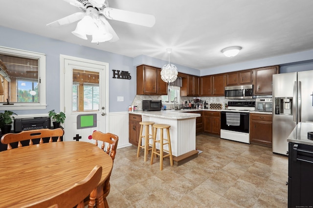 59 Litchfield Ln, Bristol, CT 06010 - kitchen with stainless steel appliances, a peninsula, light countertops, backsplash, and pendant lighting
