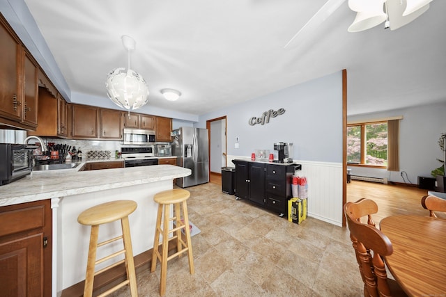59 Litchfield Ln, Bristol, CT 06010 - kitchen with stainless steel appliances, a baseboard radiator, light countertops, a peninsula, and brown cabinets