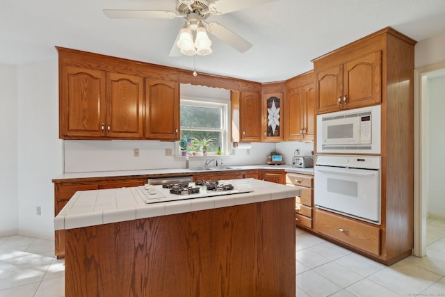 119 NW Dr, Plainville, CT 06062 - kitchen with white appliances, brown cabinetry, light tile patterned flooring, tile counters, and a kitchen island