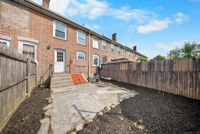 110 Asylum St, Bridgeport, CT 06610 - rear view of property featuring entry steps, a fenced backyard, a chimney, and brick siding