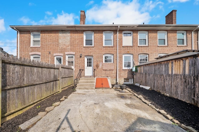 110 Asylum St, Bridgeport, CT 06610 - back of property featuring a chimney, brick siding, a fenced backyard, and entry steps