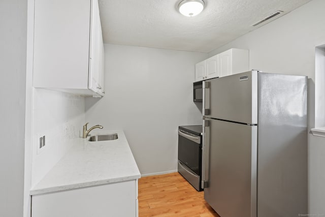 4 Union Ave Apt 30, Norwalk, CT 06851 - kitchen featuring stainless steel appliances, light wood-style flooring, white cabinets, a textured ceiling, and light stone countertops
